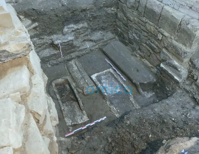 sarcophagi-late-antiquity high angle shot of a rectangular depression in stone foundations revealing four sarcophagi, one containing visible human bones.
